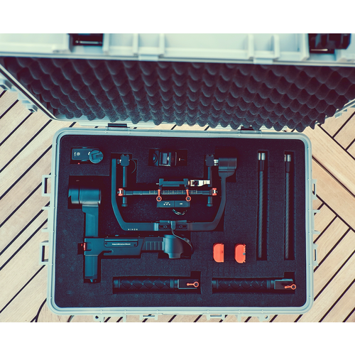 Geöffneter Koffer mit Schaumstoffeinlage, die ein Gimbal-Stabilisierungssystem und Zubehör enthält, auf Holzboden.